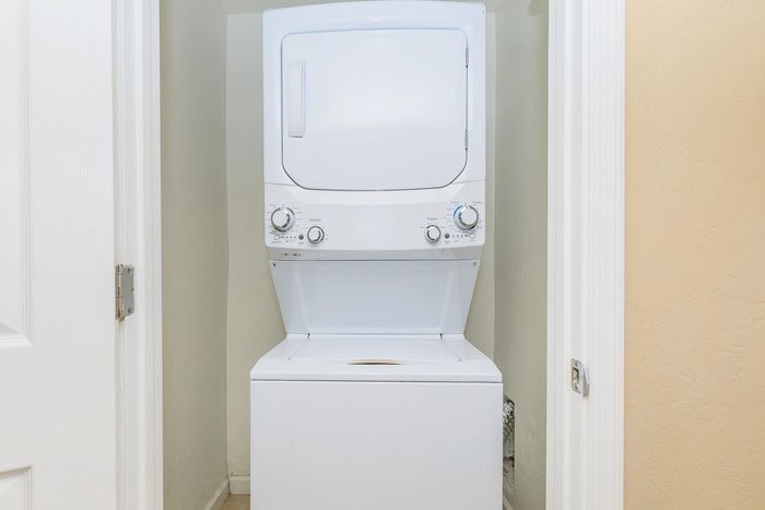 Convenient in-unit laundry featuring a sleek, white stacked washer and dryer set in a compact closet.