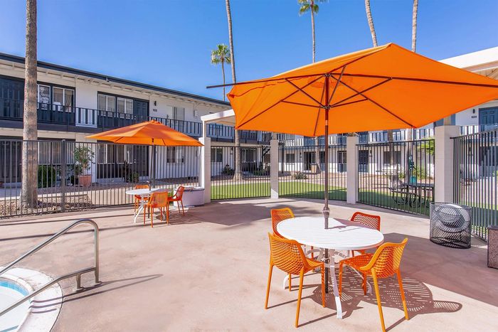 Outdoor patio with orange umbrellas and chairs at Miramonte on 3rd apartments in Tucson