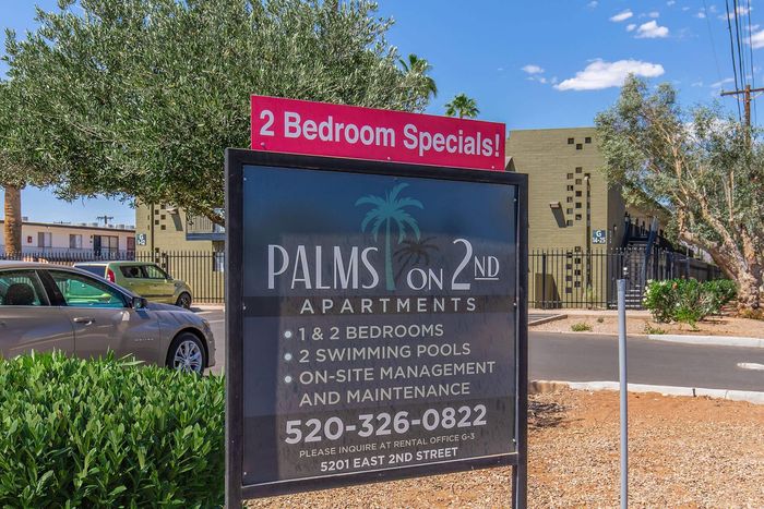 Inviting sign for Palms on 2nd Apartments showcasing 1 and 2 bedroom specials with swimming pools and on-site management.