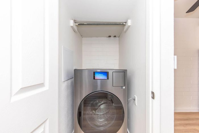 Modern laundry nook featuring a sleek, high-efficiency washing machine tucked neatly into a compact alcove, showcasing efficient use of space.