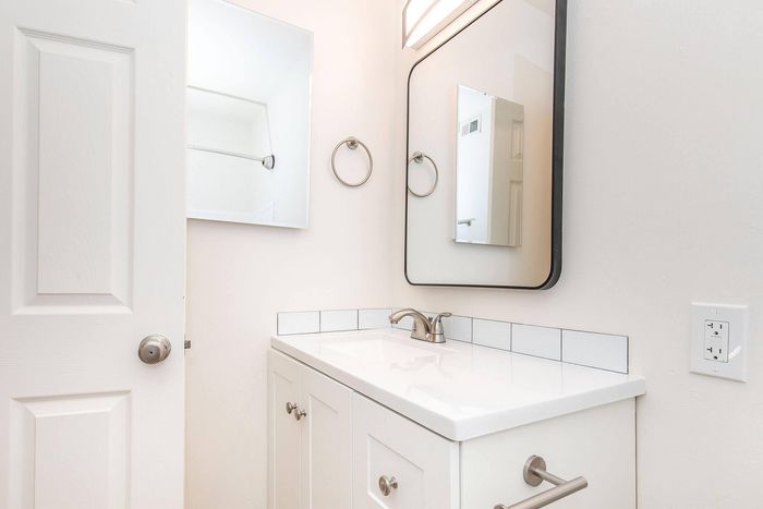 Bright, modern bathroom with sleek fixtures, featuring a spacious mirror and elegant white vanity with brushed nickel accents.