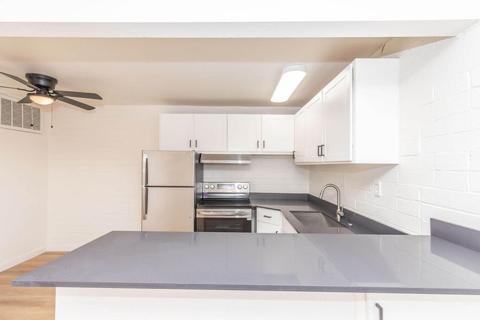 Modern kitchen with sleek stainless steel appliances, stylish white cabinetry, and a spacious countertop with overhead lighting.