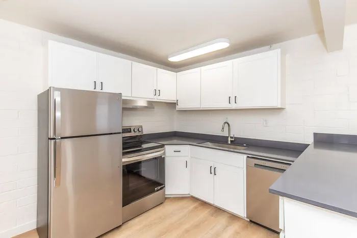 Modern kitchen with sleek stainless steel appliances, bright white cabinetry, and elegant gray countertops.