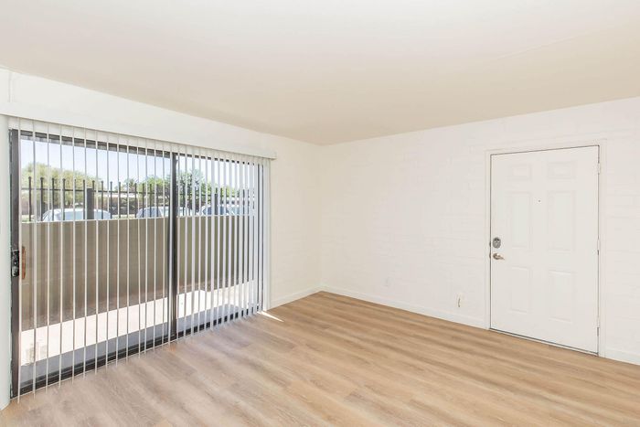 Bright living space with sleek wood flooring and expansive sliding glass doors leading to a sunlit patio area.