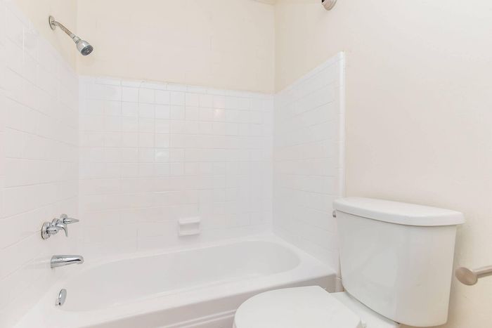 Bright, modern bathroom featuring a sleek bathtub, polished chrome fixtures, and clean white tiles, offering a fresh and relaxing retreat.