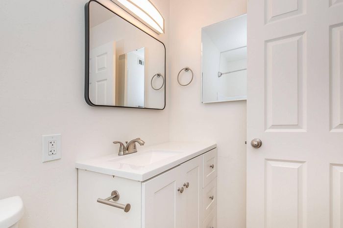 Bright, modern bathroom with sleek white vanity, elegant fixtures, and a stylish mirror in a contemporary apartment.