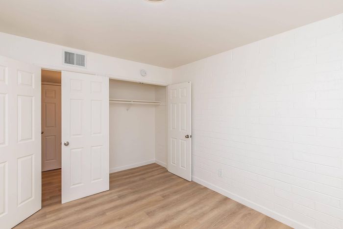Bright and airy bedroom with elegant white doors, spacious closet, and stylish wood flooring.