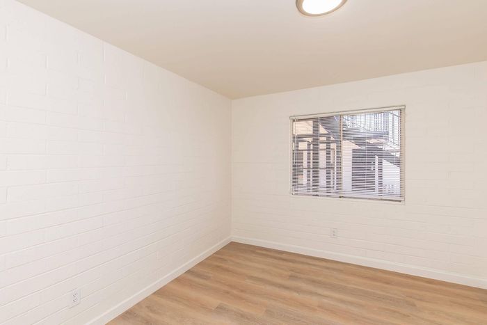 Bright and airy room with hardwood flooring and a large window offering natural light and outdoor views.