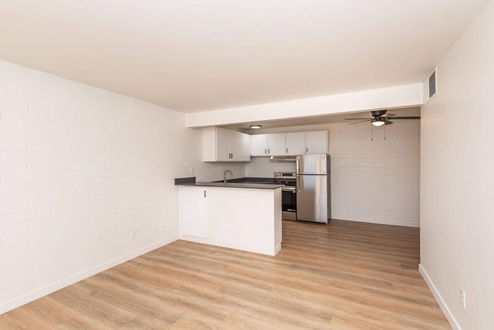 Bright open-concept kitchen with modern stainless steel appliances, sleek cabinets, and warm wood floors.