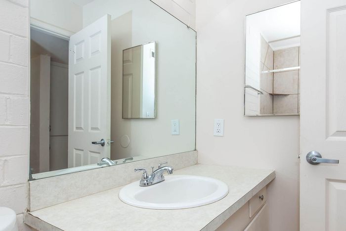 Bright and clean bathroom featuring a modern sink, elegant faucet, and ample counter space with a sleek mirror adding depth.