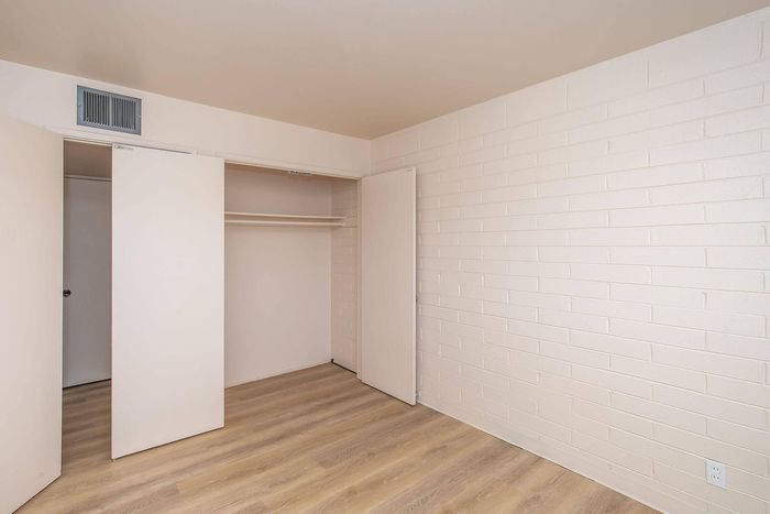 Bright, minimalist room featuring sleek wooden floors and ample closet space, perfect for a cozy bedroom or home office.