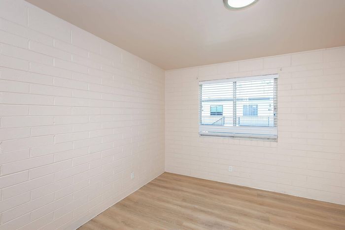 Bright and airy room with contemporary white brick walls and sleek wooden flooring, offering a fresh canvas for personalization.