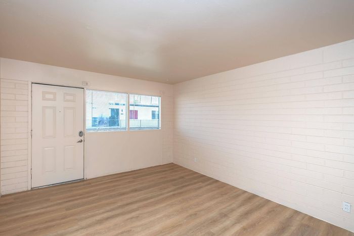 Bright apartment with elegant wood flooring, white brick walls, and abundant natural light through large windows.