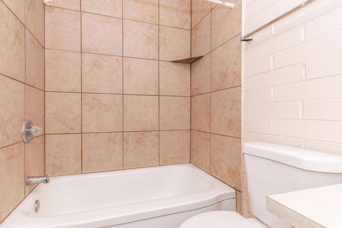 Charming bathroom with elegant beige tiles, featuring a classic bathtub and modern fixtures.