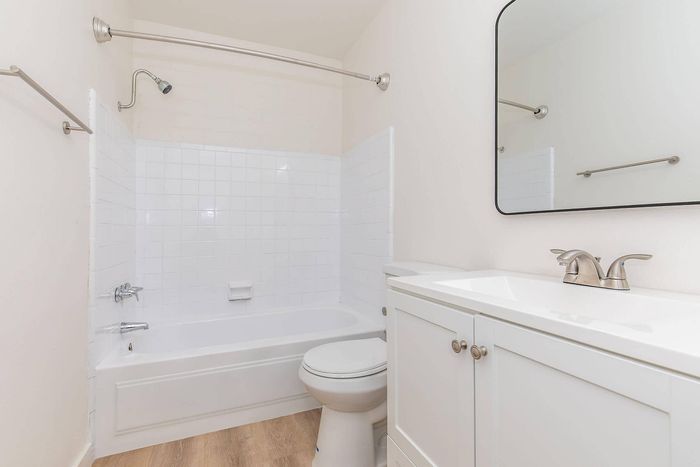 Bright and modern bathroom featuring a sleek bathtub, elegant vanity, and a stylish mirror, perfect for relaxation and refreshment.