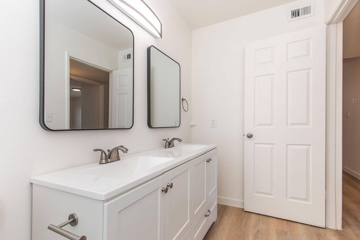 Bright and modern bathroom featuring a dual vanity with sleek mirrors and elegant fixtures.