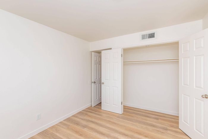 Bright and spacious empty room with wooden floors and an open closet, ready for personalization and comfort.