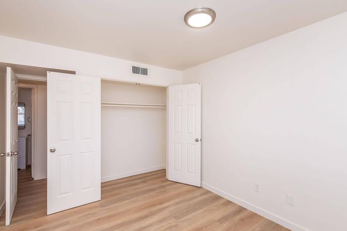 Bright and inviting bedroom with elegant wood flooring, ample closet space, and modern lighting.