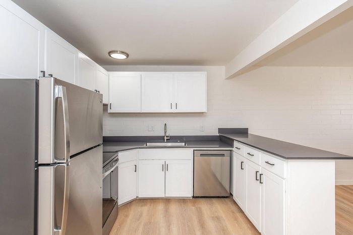 Modern kitchen design featuring sleek white cabinets, stainless steel appliances, and elegant gray countertops.