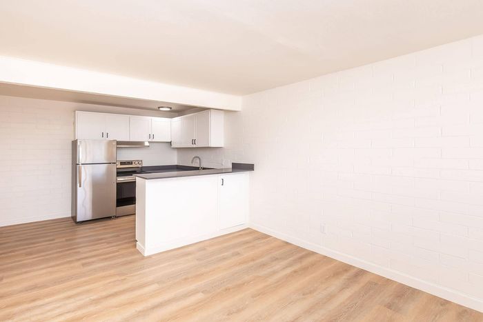 Modern kitchen space with sleek stainless steel appliances, white cabinetry, and elegant wood flooring, ideal for culinary creativity.