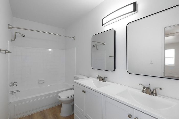 Elegant bathroom with modern fixtures, dual sinks, and a pristine white bathtub, offering a tranquil space for relaxation.