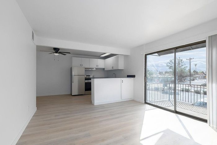 Bright open-concept kitchen and living area featuring sleek modern appliances, large sliding glass doors, and abundant natural light.