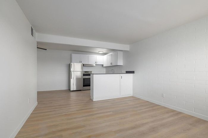 Modern apartment kitchen with sleek stainless steel appliances and elegant white cabinetry, complemented by light wood flooring.