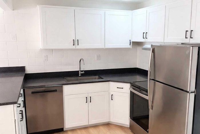 Modern kitchen with sleek stainless steel appliances, elegant white cabinetry, and spacious black countertops, offering a blend of style and functionality.