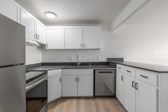 Modern kitchen with sleek white cabinetry, stainless steel appliances, and chic gray countertops.