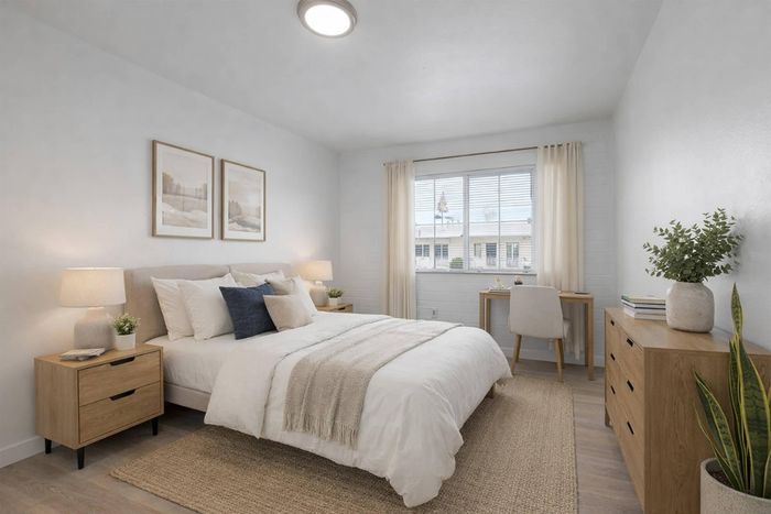 Bright and cozy bedroom featuring a plush bed, chic wooden furniture, and large window with natural light.