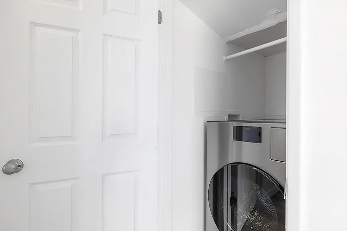 Modern laundry space with sleek stainless steel appliances and pristine white walls, offering a clean and efficient area for home chores.