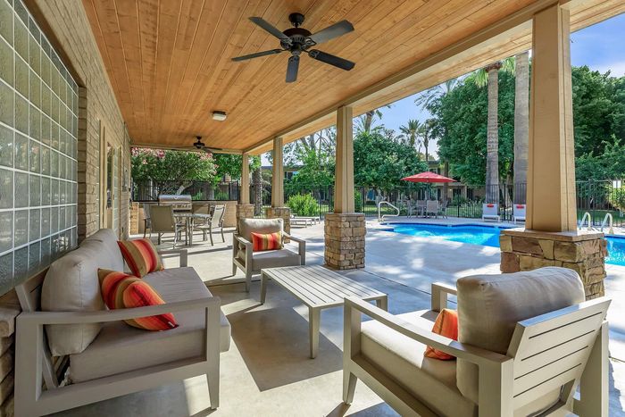 Charming outdoor patio with cozy seating overlooking a vibrant pool area, perfect for relaxation and entertaining.