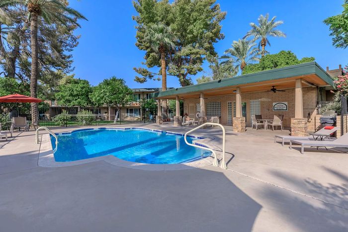 Inviting outdoor pool area with lounge chairs, umbrellas, and lush greenery, perfect for relaxation and enjoyment.