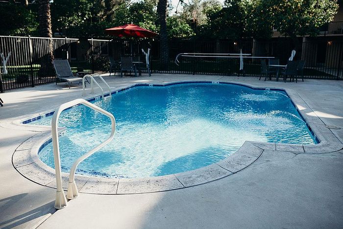 Inviting outdoor swimming pool with refreshing blue water, surrounded by lush greenery and stylish lounge chairs.