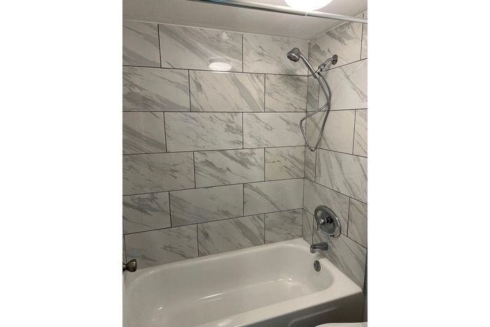 Elegant bathroom featuring modern silver fixtures and glossy white marble tiles.