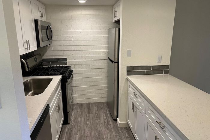 Modern kitchen with sleek stainless steel appliances, white cabinetry, and elegant quartz countertops.
