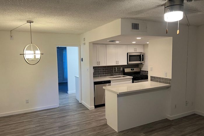 Modern open-concept kitchen with sleek white cabinetry, stainless steel appliances, and inviting dining area with stylish lighting.