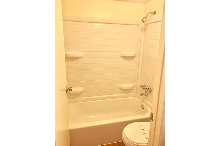 Bright and inviting bathroom with modern white tiles, gleaming fixtures, and a cozy bathtub setup.