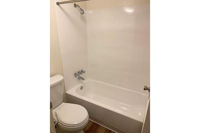Bright, clean bathroom with modern white tiles and a spacious bathtub, offering a serene retreat.