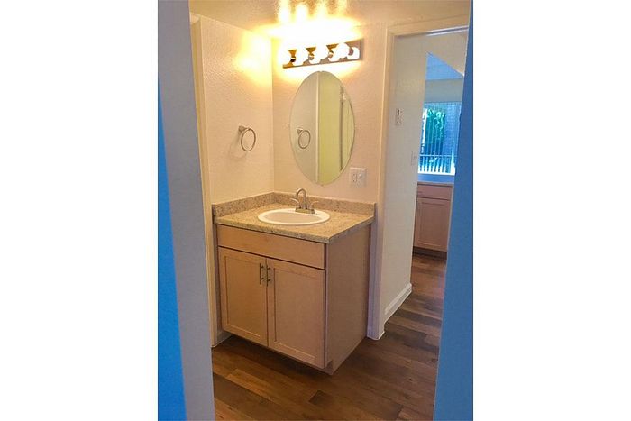 Inviting bathroom with elegant lighting, oval mirror, and stylish wood cabinetry, offering a cozy and functional design.