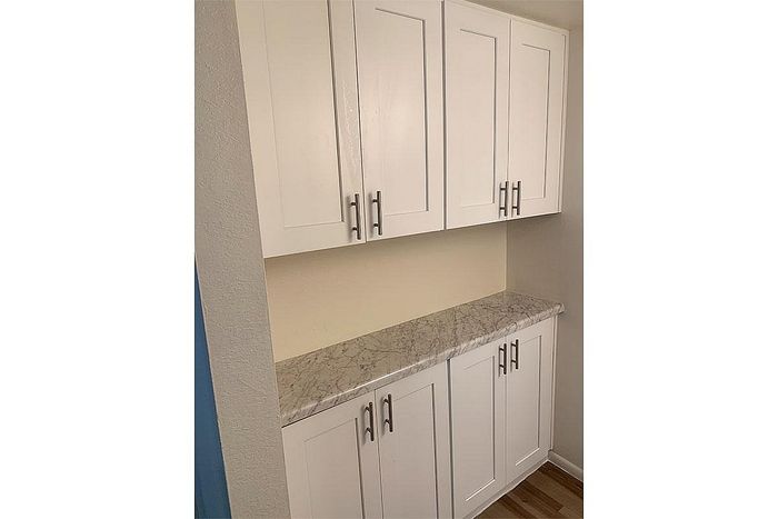 Elegant kitchen storage with white cabinets and sleek marble countertop, offering ample space and modern style.