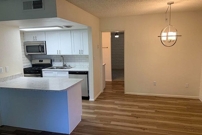 Modern kitchen with sleek white cabinetry, stainless steel appliances, and elegant wood flooring.