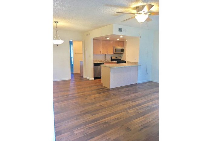 Bright open-plan kitchen with elegant wooden flooring and modern appliances.
