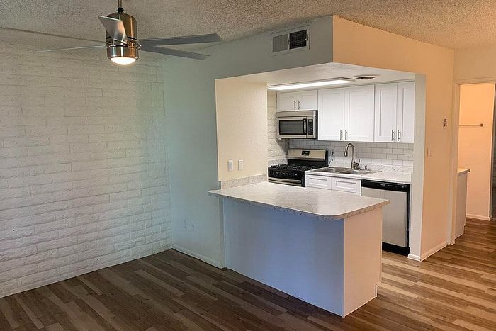 Inviting open-concept apartment with modern kitchen, sleek white cabinetry, and elegant laminate flooring.