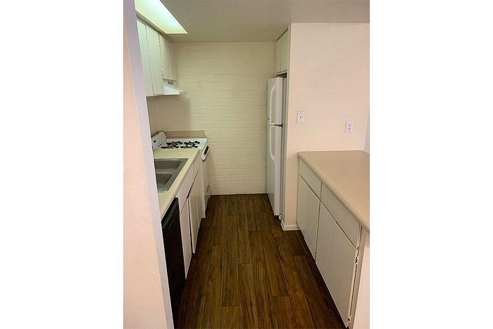 Charming galley kitchen with sleek appliances and warm wood flooring, perfect for culinary creativity.