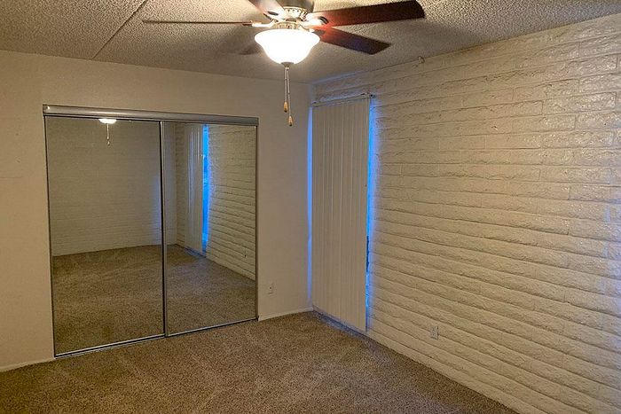 Inviting room featuring a mirrored closet, plush carpeting, and soft lighting under a ceiling fan.