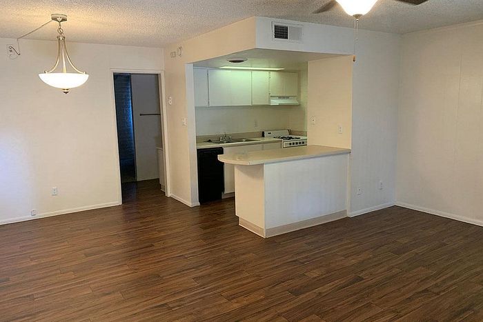 Elegant open-plan apartment featuring sleek wood flooring, a bright kitchen with a cozy breakfast bar, and stylish lighting.