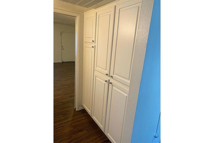 Bright hallway with elegant white cabinetry and rich hardwood flooring, leading to a spacious entryway.