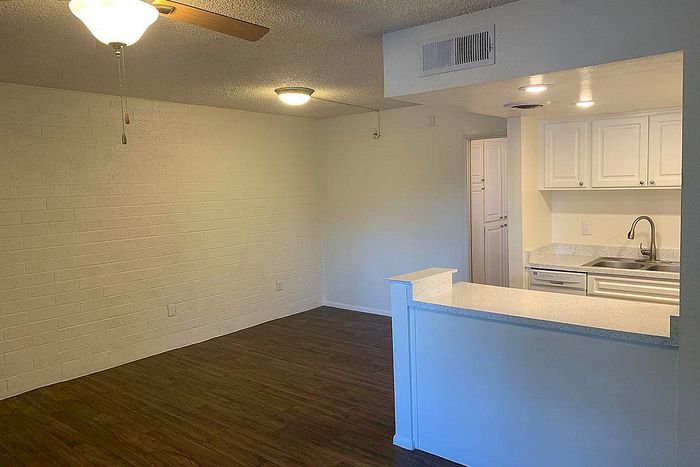Inviting open-plan living space with warm wood flooring, modern lighting, and a sleek kitchen with ample cabinetry.
