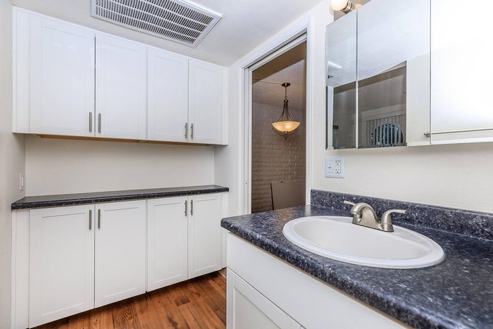 Sleek modern bathroom with elegant white cabinetry, dark granite countertops, and a polished sink with chrome fixtures.